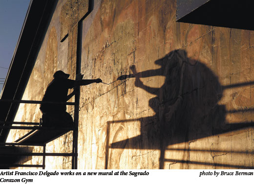 Artist Francisco Delgado works on a new mural at the Sagrado Corazon Gym