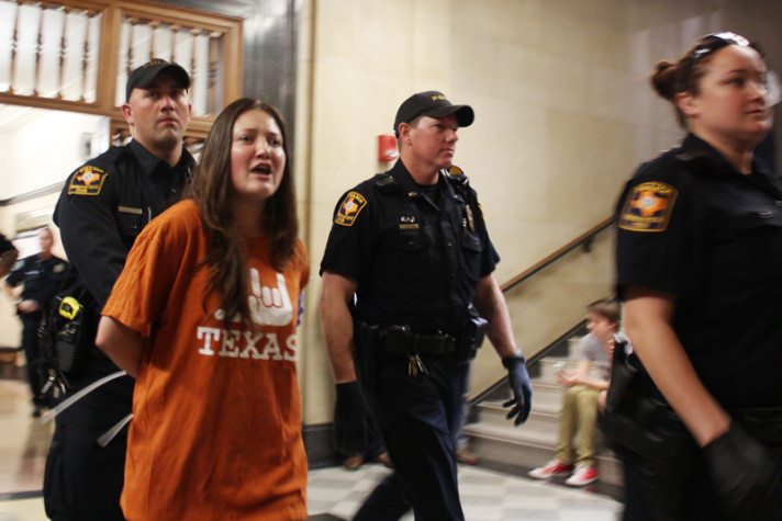 University of Texas police lead a protester away from a demonstration outside UT-Austin President Bill Powers' office Wednesday afternoon.
