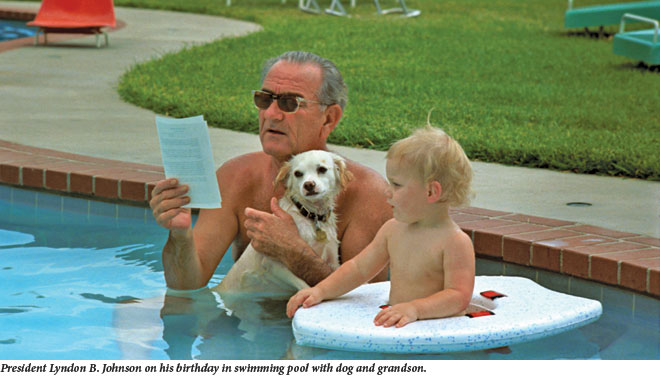 President Lyndon B. Johnson on his birthday in pool with dog and grandson
