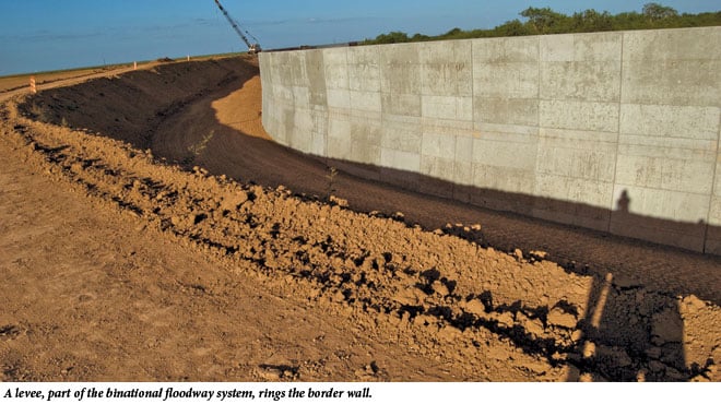 A levee, part of the binational floodway system, rings the border wall.