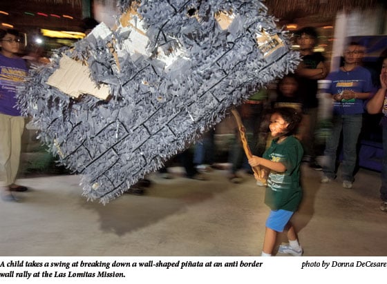 A child takes a swing at breaking down a wall-shaped piÃ’ata at an anti border wall rally at the Las Lomitas Mission.