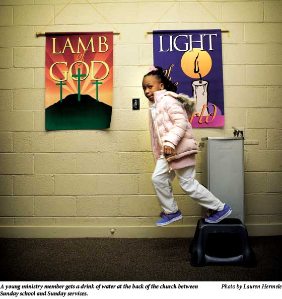 A young ministry member gets a drink of water at the back of the church between Sunday school and Sunday services.