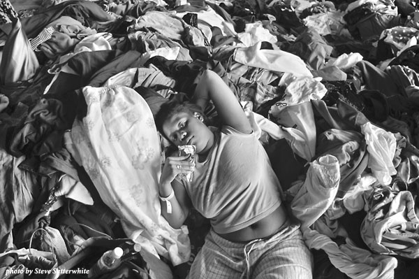 Young girl lying on a pile of clothes and other donated items