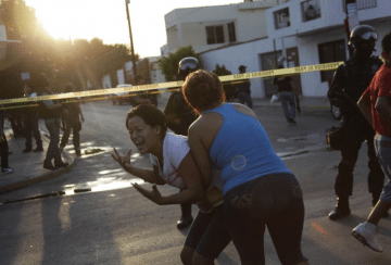 A woman is held back by another woman as she reacts to the killing of several people at a crime scene in Monterrey on August 29, 2012. Gunmen shot dead three men and a woman and left graffiti on a wall at the crime scene reading