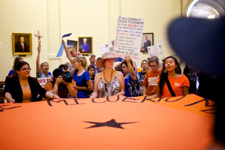 Pro-choice demonstrators wave a banner in the rotunda as an anti-abortion crowd holds crosses and signs behind them.