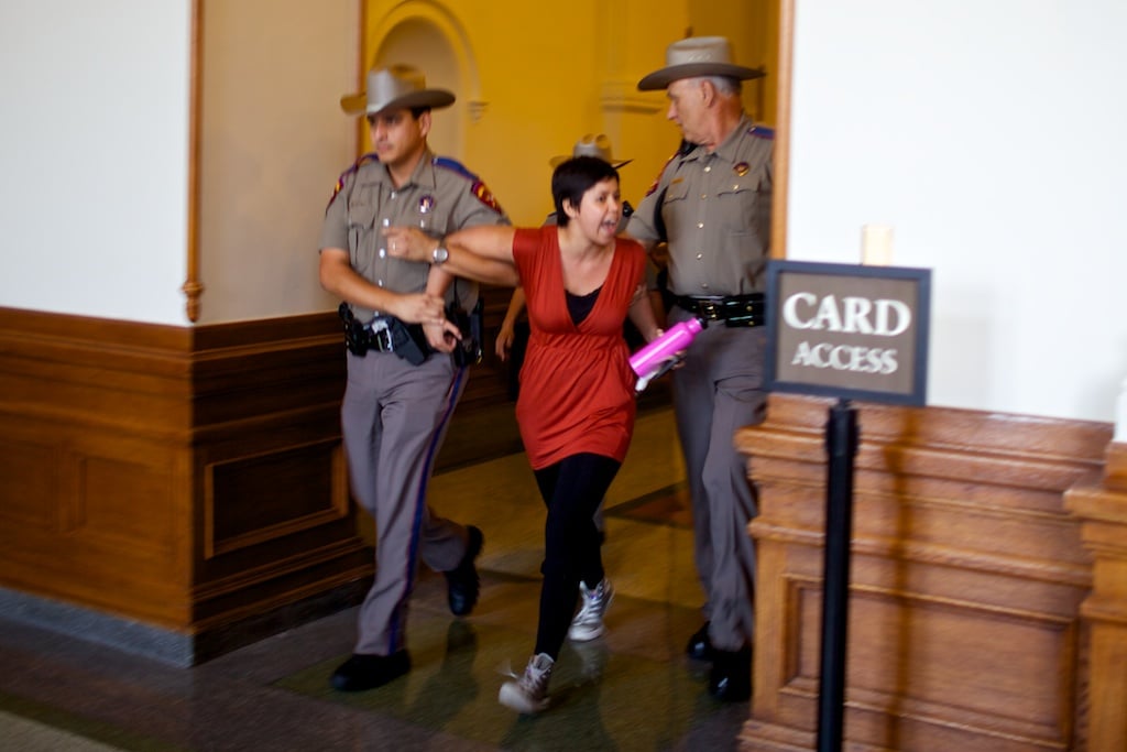 Troopers lead a woman out the Capitol's east doors Friday evening.