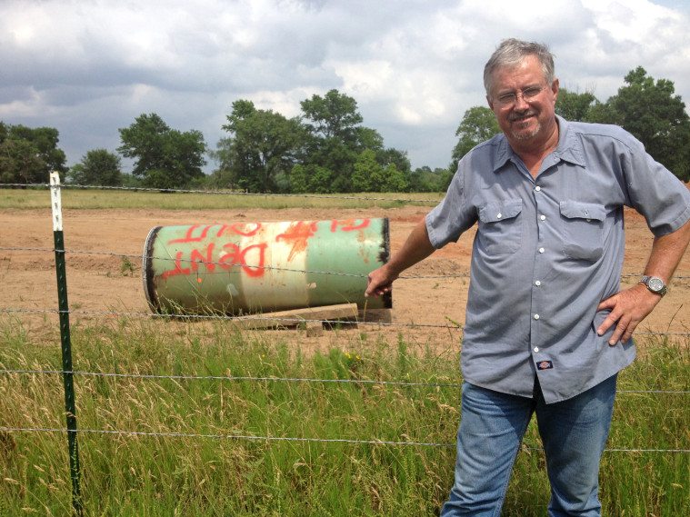 David Whitley stands near the dented pipe cutout he found on his property near Winnsboro.