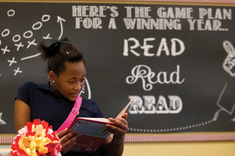 Meisha Washington reads a book in the newly reopened library at Houston’s Hogg Middle School. The library had closed due to state budget cuts