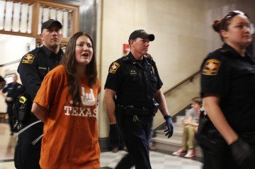 University of Texas police lead a protester away from a demonstration outside UT-Austin President Bill Powers' office Wednesday afternoon.