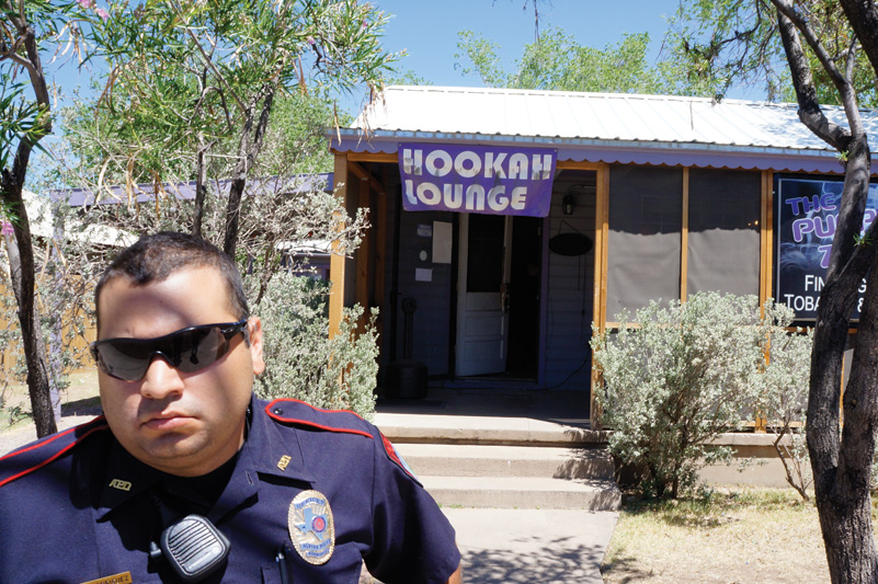 An Alpine police officer stands watch outside the Purple Zone smoke shop during a federal raid in May.