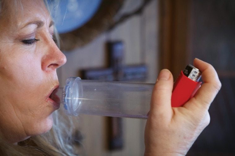 Lori Collins uses an inhaler to address respiratory problems that began after mold appeared in her home.