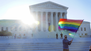 An LGBT rights supporter waves a flag in front of the U.S. Supreme Court.