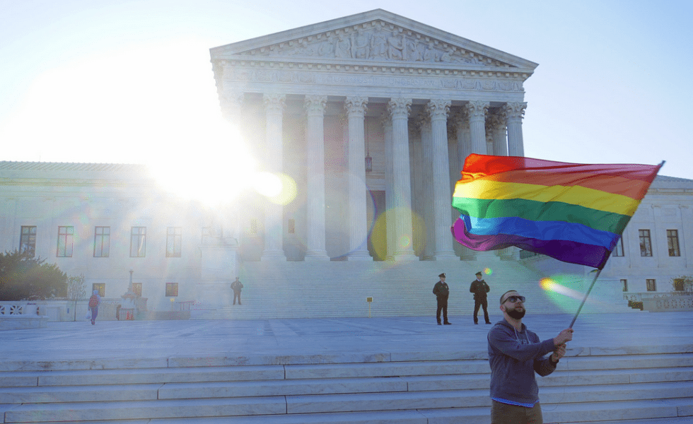 An LGBT rights supporter waves a flag in front of the U.S. Supreme Court.