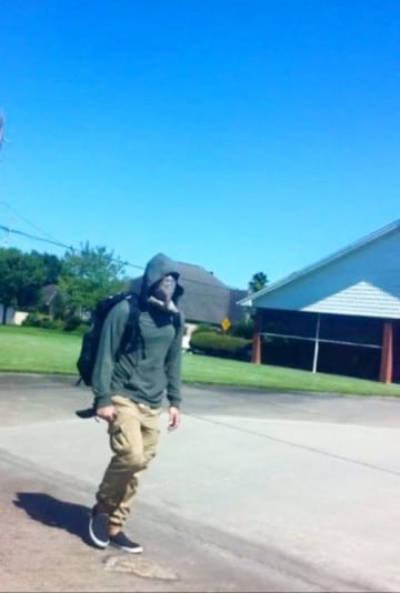 A man wearing a hoodie and a bandana over his face carries a knife.