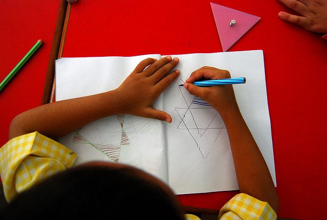 A child draws at a school desk.