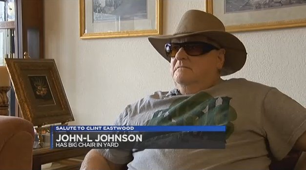 Giant chair owner John L. Johnson wearing a brimmed hat and sunglasses.