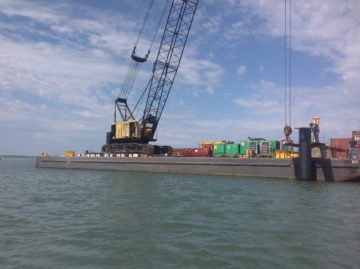 A crane lowers a metal piling to be used to tie off barges in the Lydia Ann Channel.