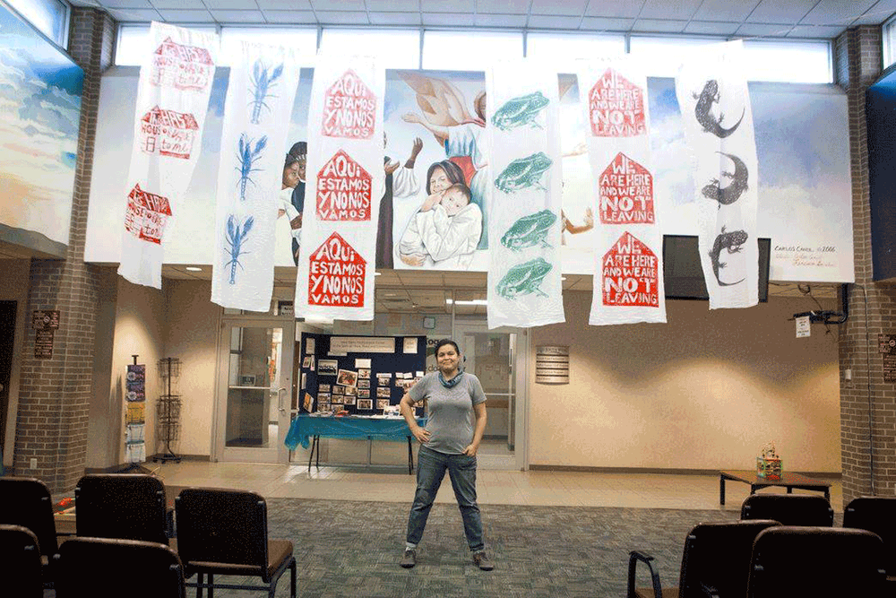 Artist Angela Faz stands below her piece for Decolonize Dallas at the West Dallas Multipurpose Center.