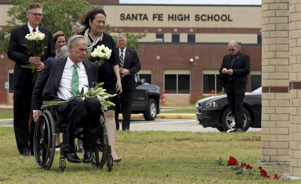 Governor Greg Abbott, his wife, Cecilia, and Lieutenant Governor Dan Patrick prepare to place flowers at Santa Fe High School, where a gunman killed 10 people.