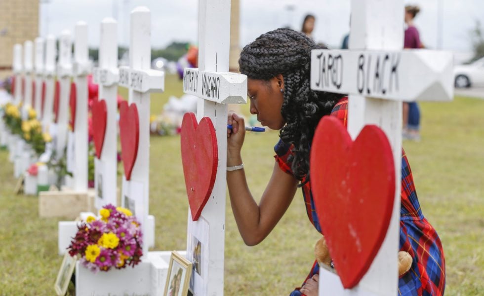 Santa Fe High School freshman Jai Gillard writes messages on each of the 10 crosses in front the school. Gillard witnessed the shooting.