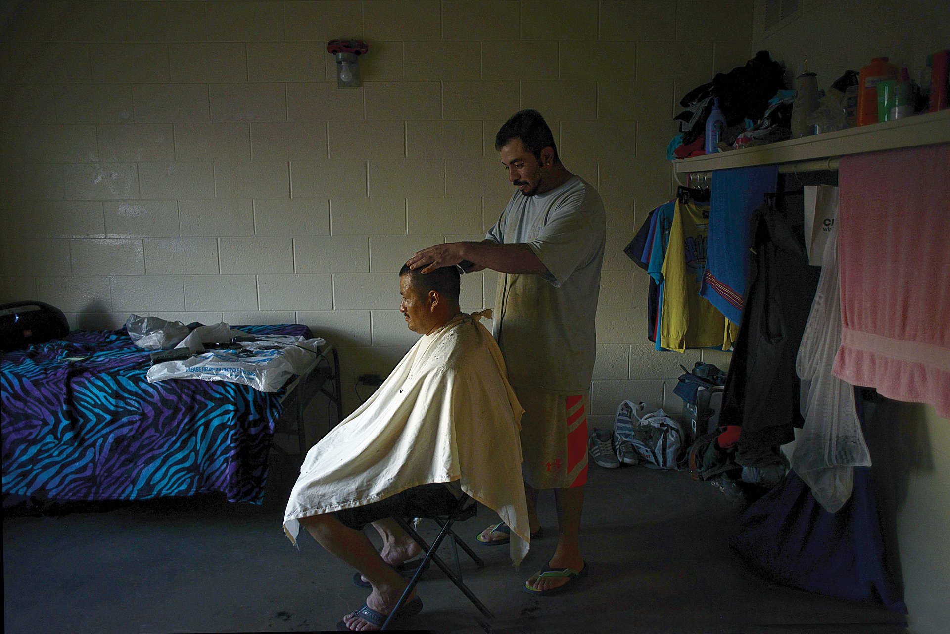 After a long day in the fields, Juan gives his colleague a haircut in the dwindling daylight. "My wife does this [hairdressing] in Mexico, and I'm actually pretty good," he says. With no cars or connection to the local community, and most of their earnings sent home, the men depend on each other for support.