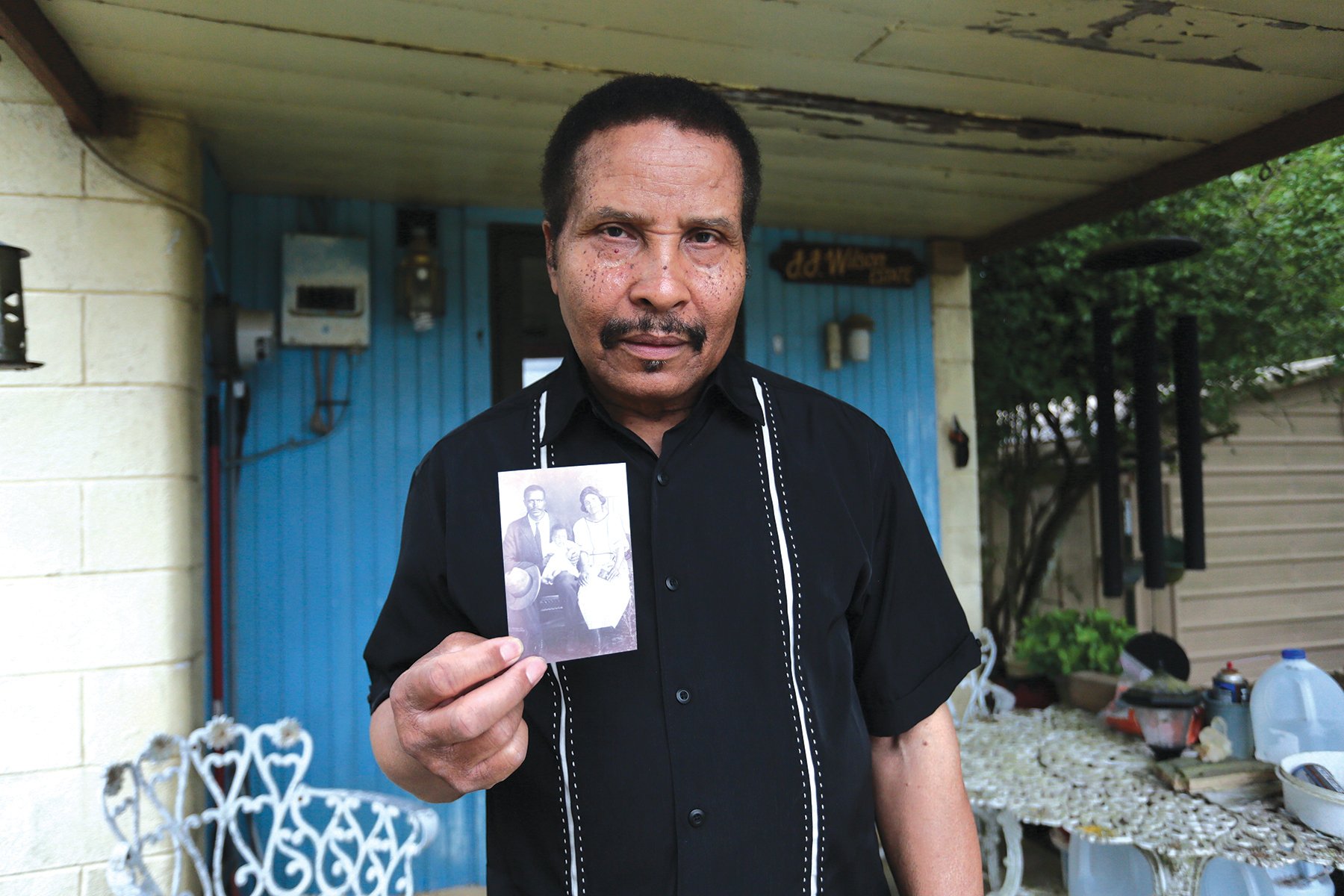 Winston Wilson shows an old photo of his father, who survived the massacre. He still lives on the property his parents fled to in 1910.