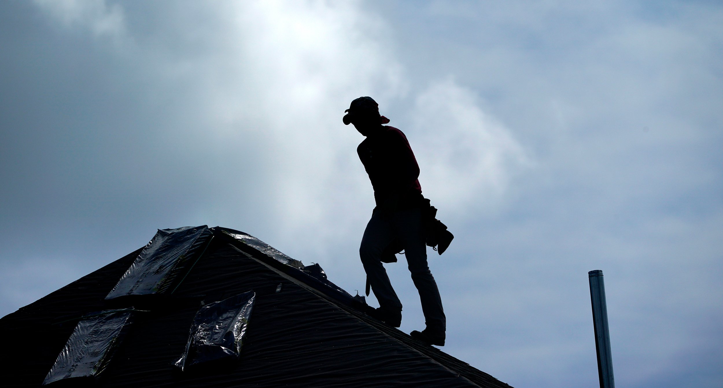 A roofer works on a new home under construction Thursday, July 18, 2019, in Houston. A heat wave is expected to send temperatures soaring close to 100 degrees through the weekend across much of the country. The National Weather Service estimates that more than 100 heat records will fall on Saturday. Most will not be the scorching daily highs, but for lack of cooling at night, something called nighttime lows. Those lows will be record highs. (AP Photo/David J. Phillip)