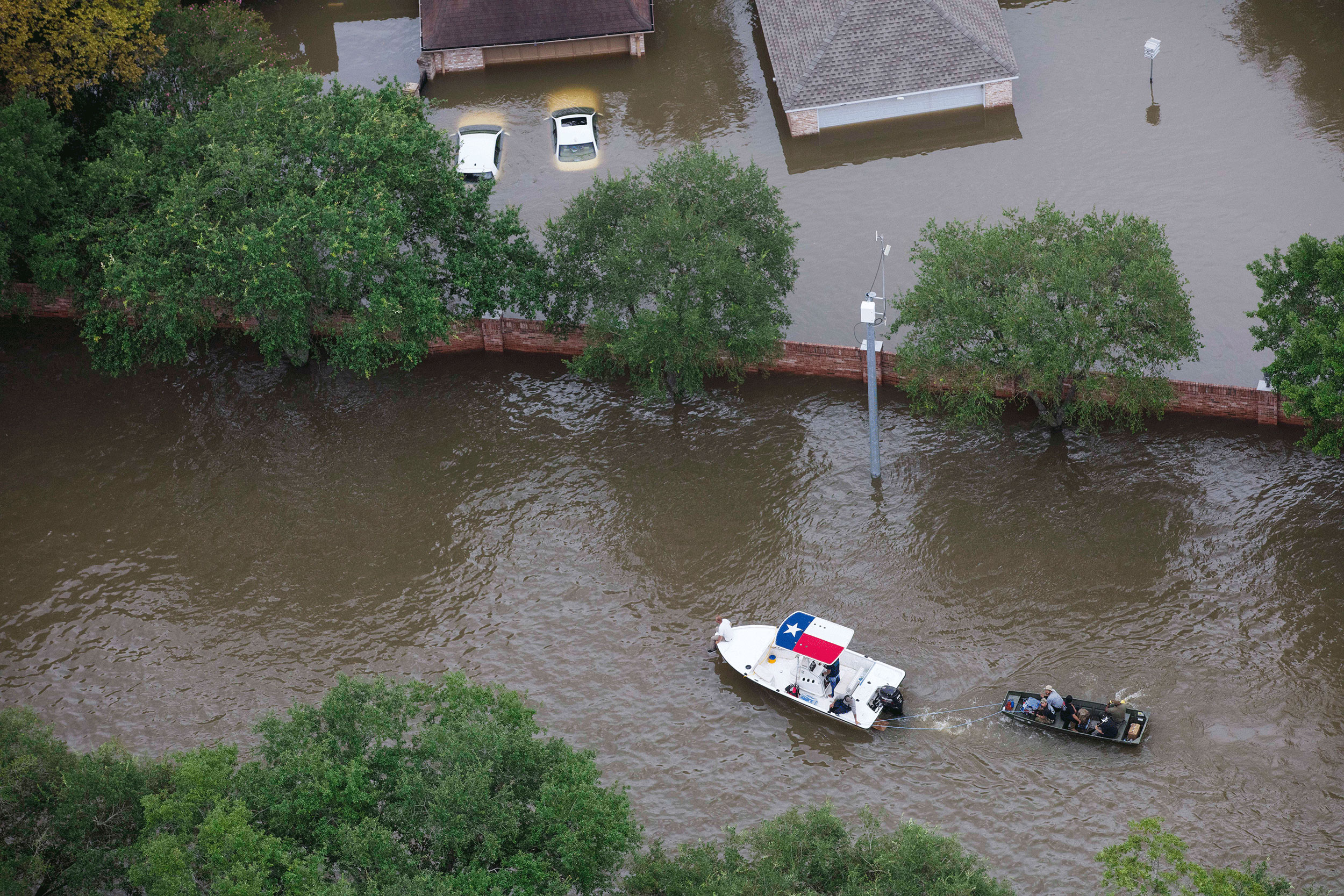 A boat with the Texas state flag on the roof tows another boat.