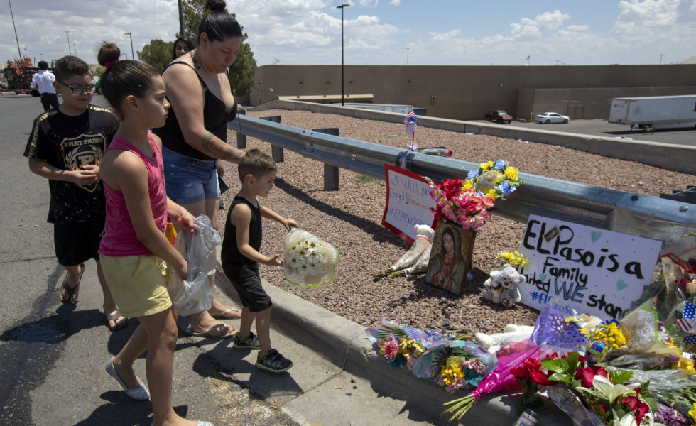 An El Paso family brings flowers to the makeshift memorial for the victims of Saturday’s mass shooting at a shopping complex in El Paso.