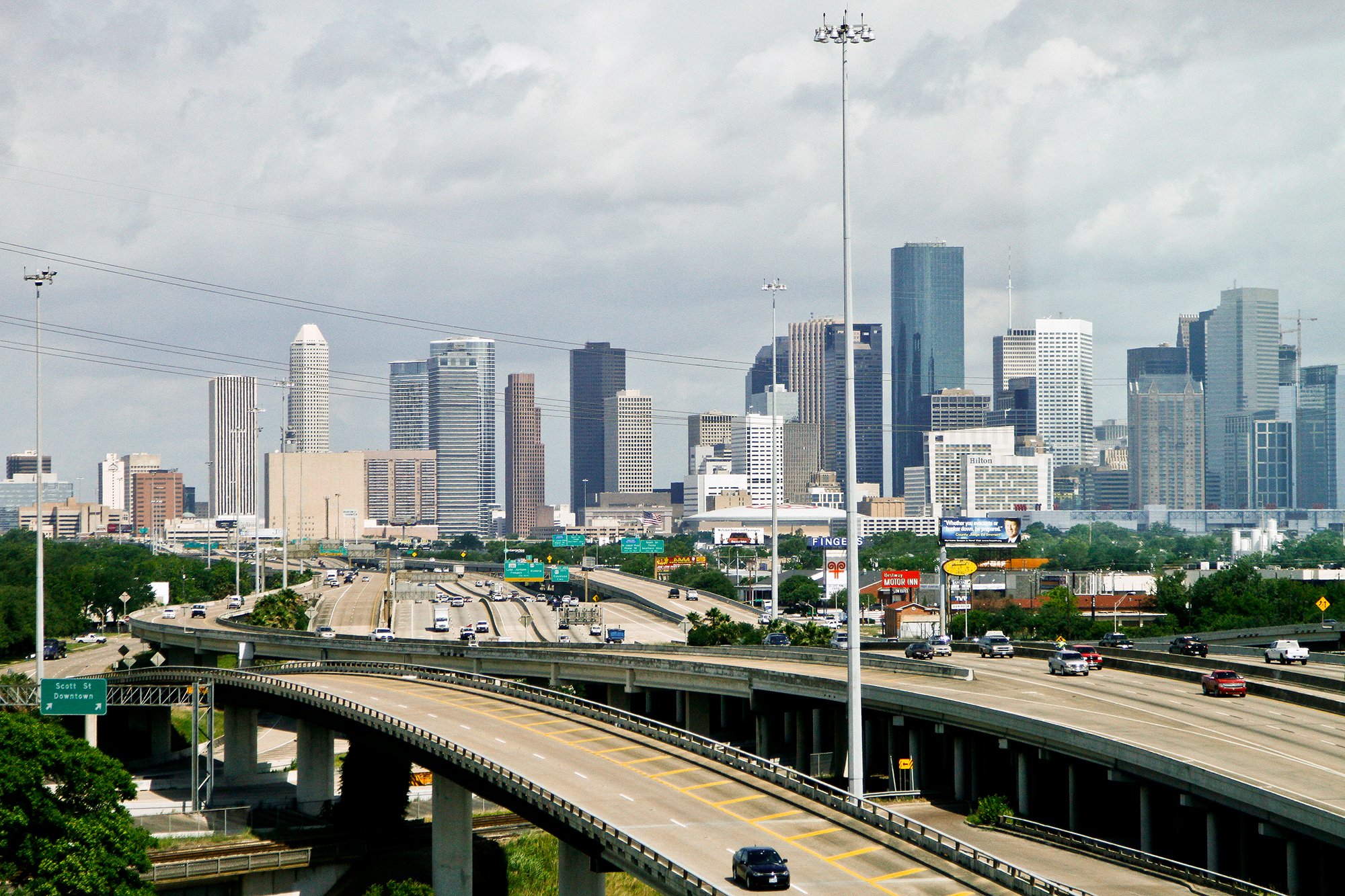 Cars travel along a highway with the skyline of downtown Houston in the background.