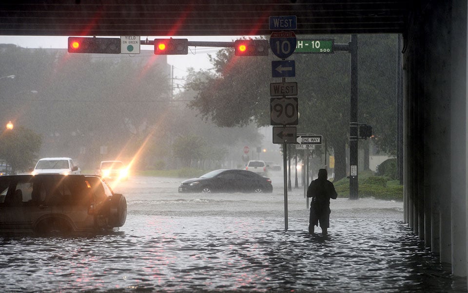 A man makes his way under the I-10 overpass where several roads remained heavily flooded throughout the afternoon, Thursday, Sept. 19, 2019 in Beaumont, Texas. The slow-churning remnants of Tropical Storm Imelda dangerously flooded parts of Texas and Louisiana on Thursday, leaving at least two people dead and rescue crews and volunteers with boats scrambling to reach scores of stranded drivers and families trapped in their homes. (Kim Brent/The Beaumont Enterprise via AP)
