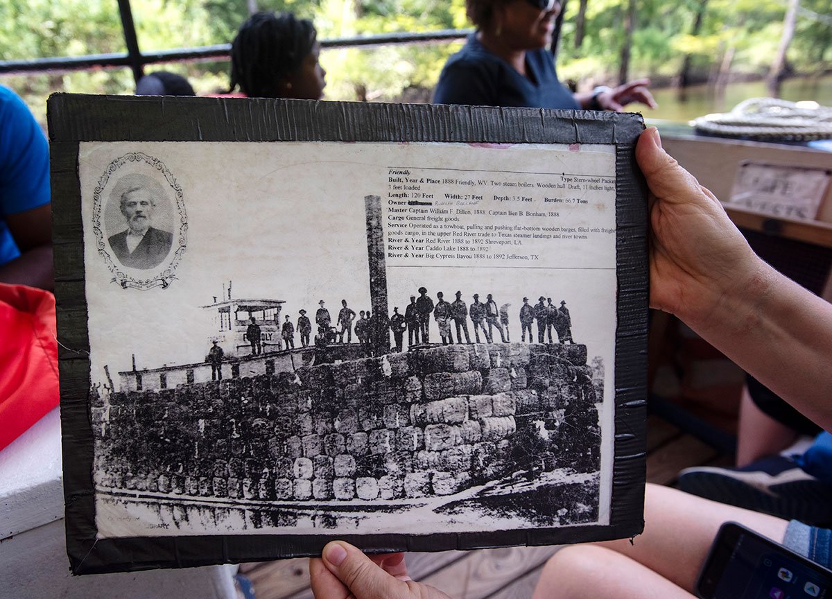 Claudia Orwig of Daingerfield looks at a historical photograph of a steamboat carrying cotton between East Texas and Louisiana that is being passed around the boat on a riverboat tour by Turning Basin Tours in Jefferson, Texas on Friday July 26, 2019. The one hour tours include history and nature information.