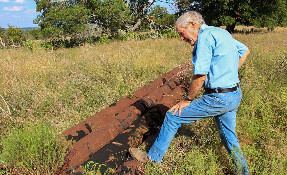 Andrew Sansom with some remaining pipe sections from an old pipeline on his land that was mostly removed in 2011, on September 13, 2019.