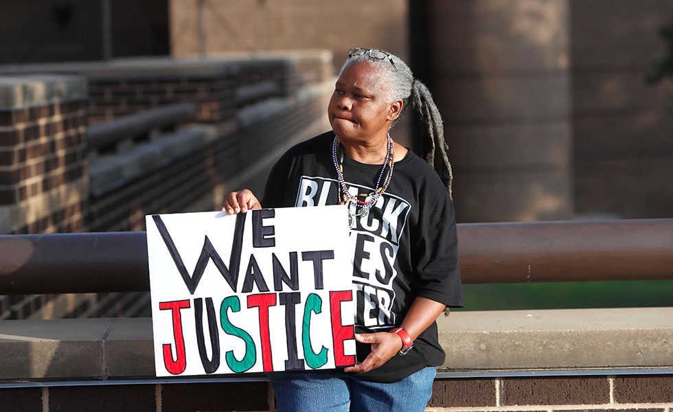 Alpha Thomas holds a sign outside the Frank Crowley Courthouse before the start of the murder trial of former Dallas police Officer Amber Guyger in downtown Dallas, Monday, Sept. 23, 2019. Guyger is on trial for shooting and killing her unarmed neighbor Botham Jean in the Dallas apartment building they both lived in. (AP Photo/LM Otero)