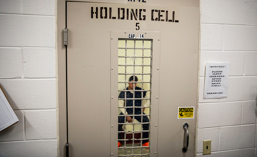 A detainee sits in a holding cell at the Stewart Detention Center, Friday, Nov. 15, 2019, in Lumpkin, Ga. The city's 1,172 residents are outnumbered by the roughly 1,650 male detainees that ICE said were being held in the detention center in late November. (AP Photo/David Goldman)