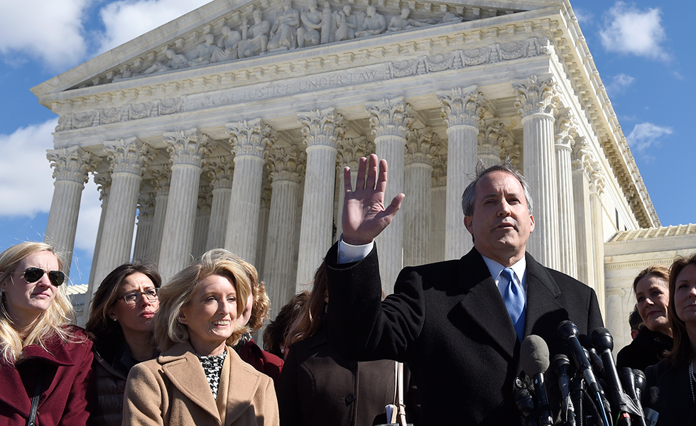 Texas Attorney General Ken Paxton, right, speaks to reporters outside the Supreme Court in Washington, Wednesday, March 2, 2016, after the court heard arguments over Texas abortion clinic regulations in its biggest abortion case in nearly a quarter-century. Texas State Rep. Jodie Laubenberg, listens, third from left. (AP Photo/Susan Walsh)