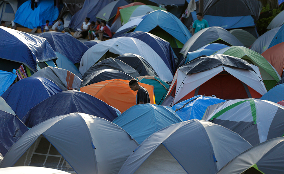 In this Tuesday, Nov. 5, 2019, photo, a migrant walks through a refugee camp in Matamoros, Mexico. The camp is an outgrowth of the Trump administration’s “Remain in Mexico” program, in which more than 55,000 migrants seeking entry into the U.S. have been ordered to pursue their cases outside its borders. (AP Photo/Eric Gay)