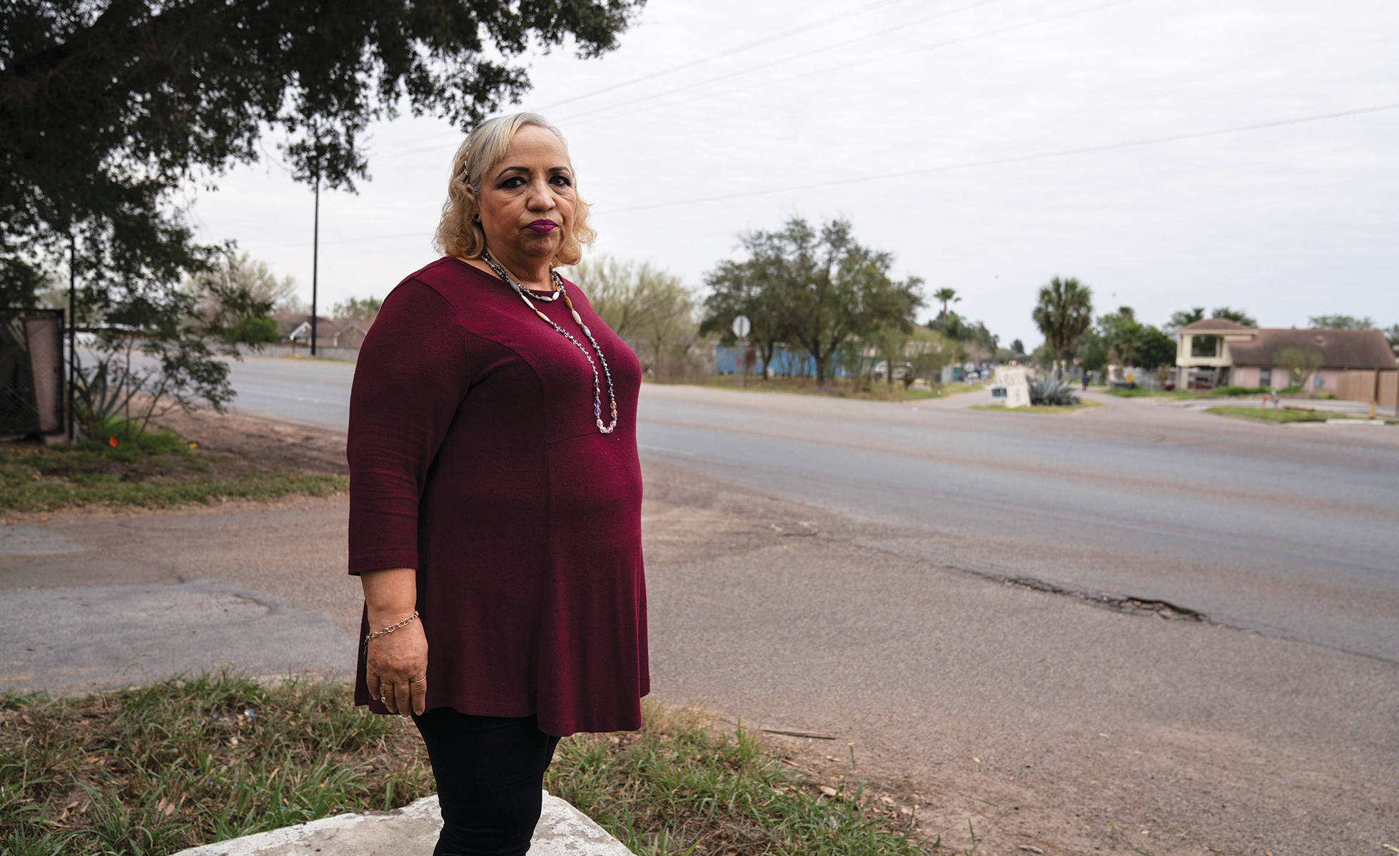Lourdes Salinas stands in the elevated spot where she made phone calls and helped to evacuate residents during the June 2018 flood.