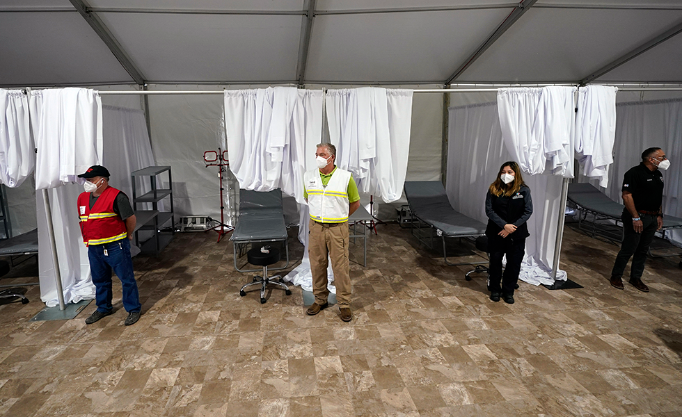 Medical professionals wait by empty beds during a tour of the new Harris County Non-Congregate Medical Shelter at NRG Park Saturday, April 11, 2020, in Houston. The new temporary setup will have 250 beds initially with a capacity of 2000 beds, if needed, to help relieve pressure on the hospital system from COVID-19 patients. Activation is not intended at this time. (AP Photo/David J. Phillip)