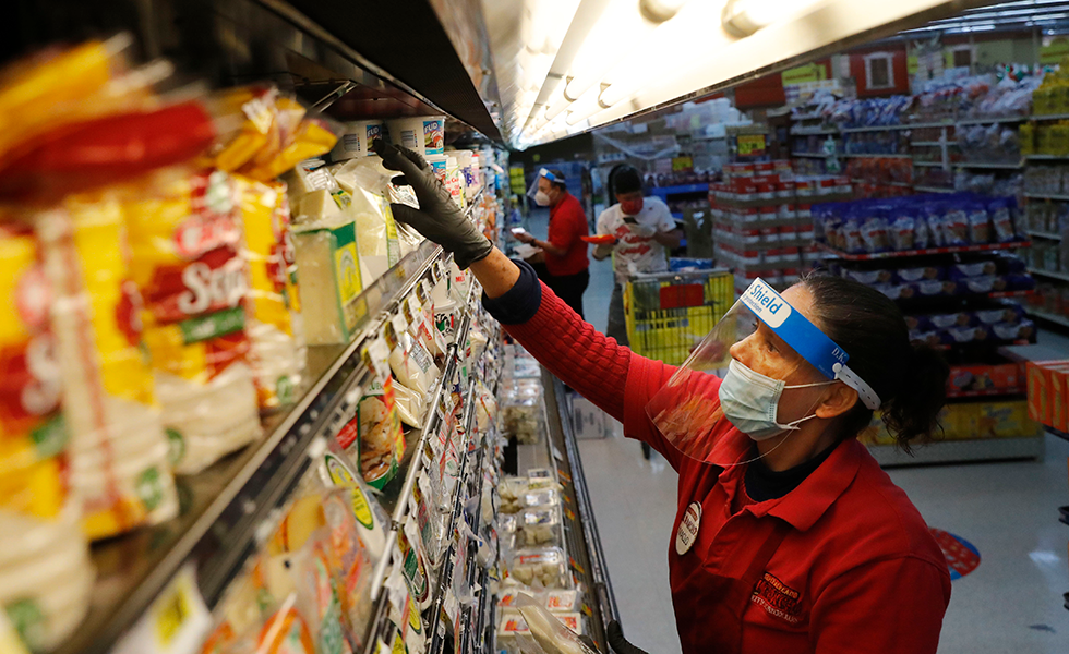 Maclola Orozco wears protective gear as a precaution against the coronavirus as she restocks shelves at El Rancho grocery store in Dallas, Monday, April 13, 2020. (AP Photo/LM Otero)