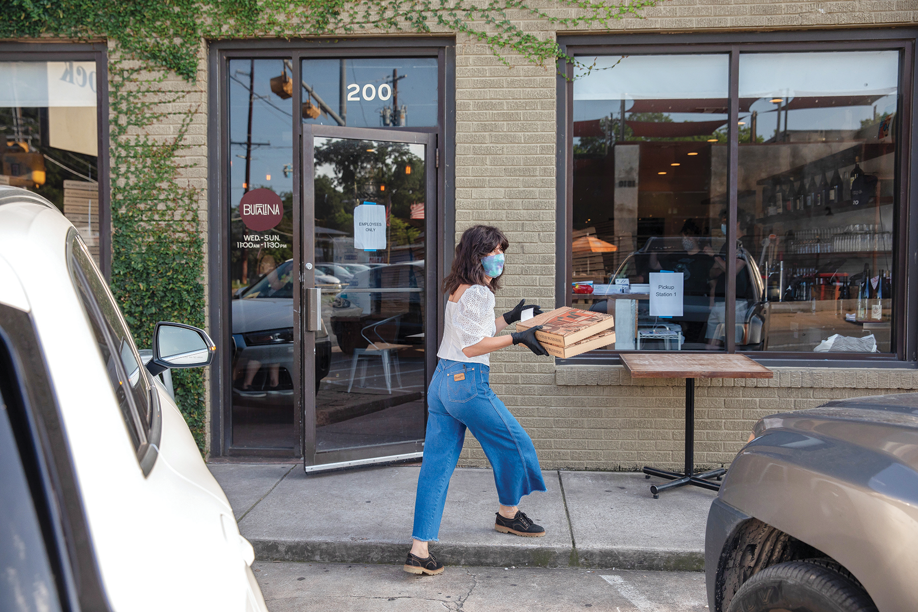 An employee at Bufalina delivers takeout pizzas to customers waiting outside.