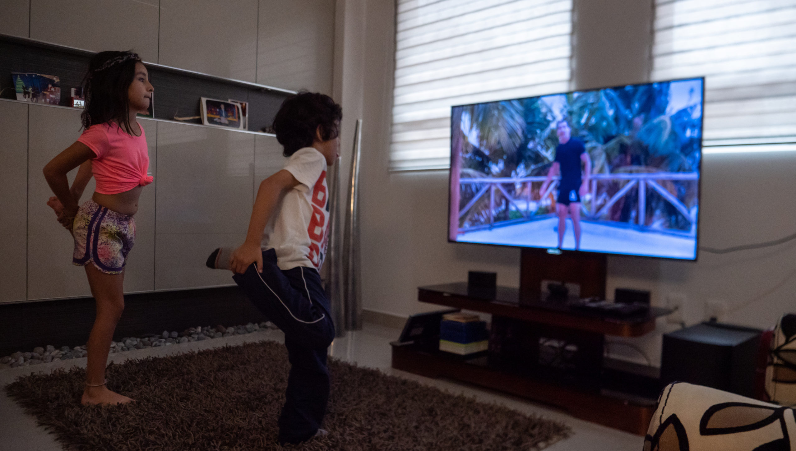 Ivanna and Alonso Granados exercise in their living room through a televised PE class that's part of the Mexican Government's at-home learning program.