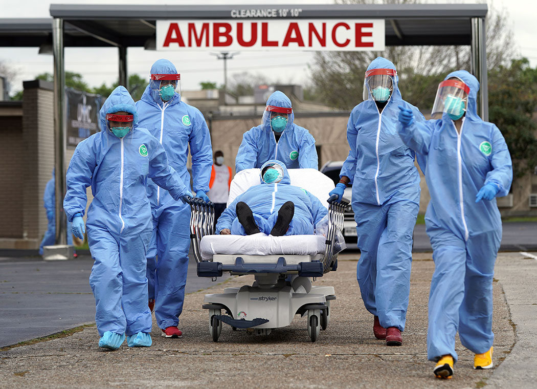 Someone is taken into a Houston hospital in March from a drive-through COVID-19 testing site, where cars formed a 2-mile line for tests. The patient is lying on a stretcher, escorted by a team of medics in full body protective gear.