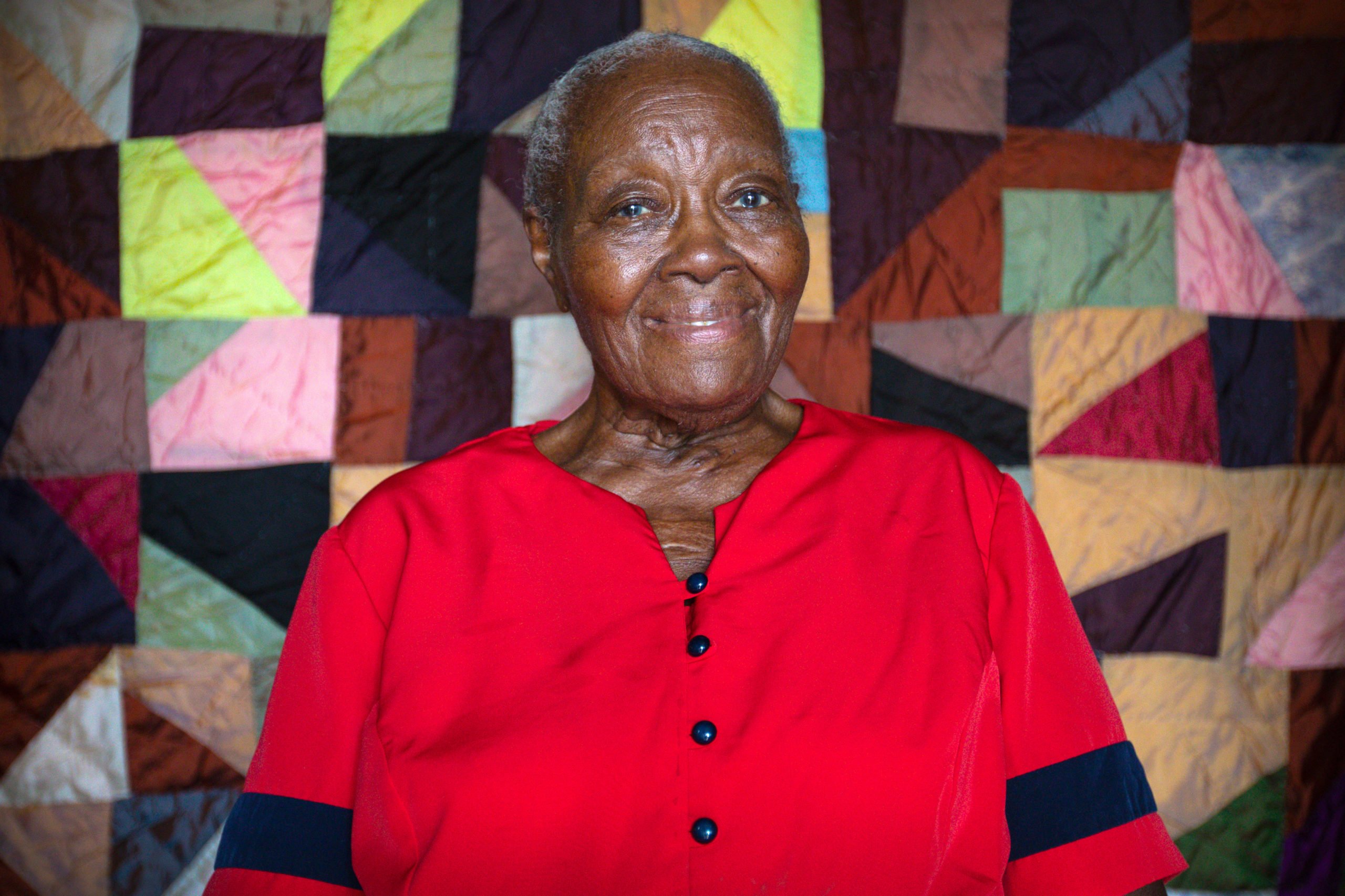 Laverne Brackens sits in front of one of her early quilts made with silk from Japan