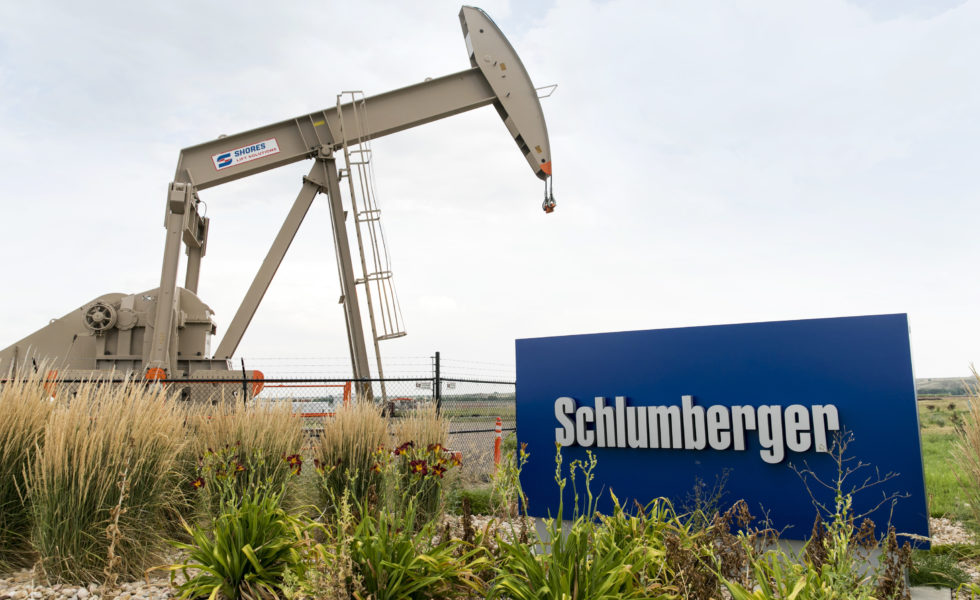 A logo sign and oil pump outside of a facility occupied by Schlumberger in Windsor, Colorado.