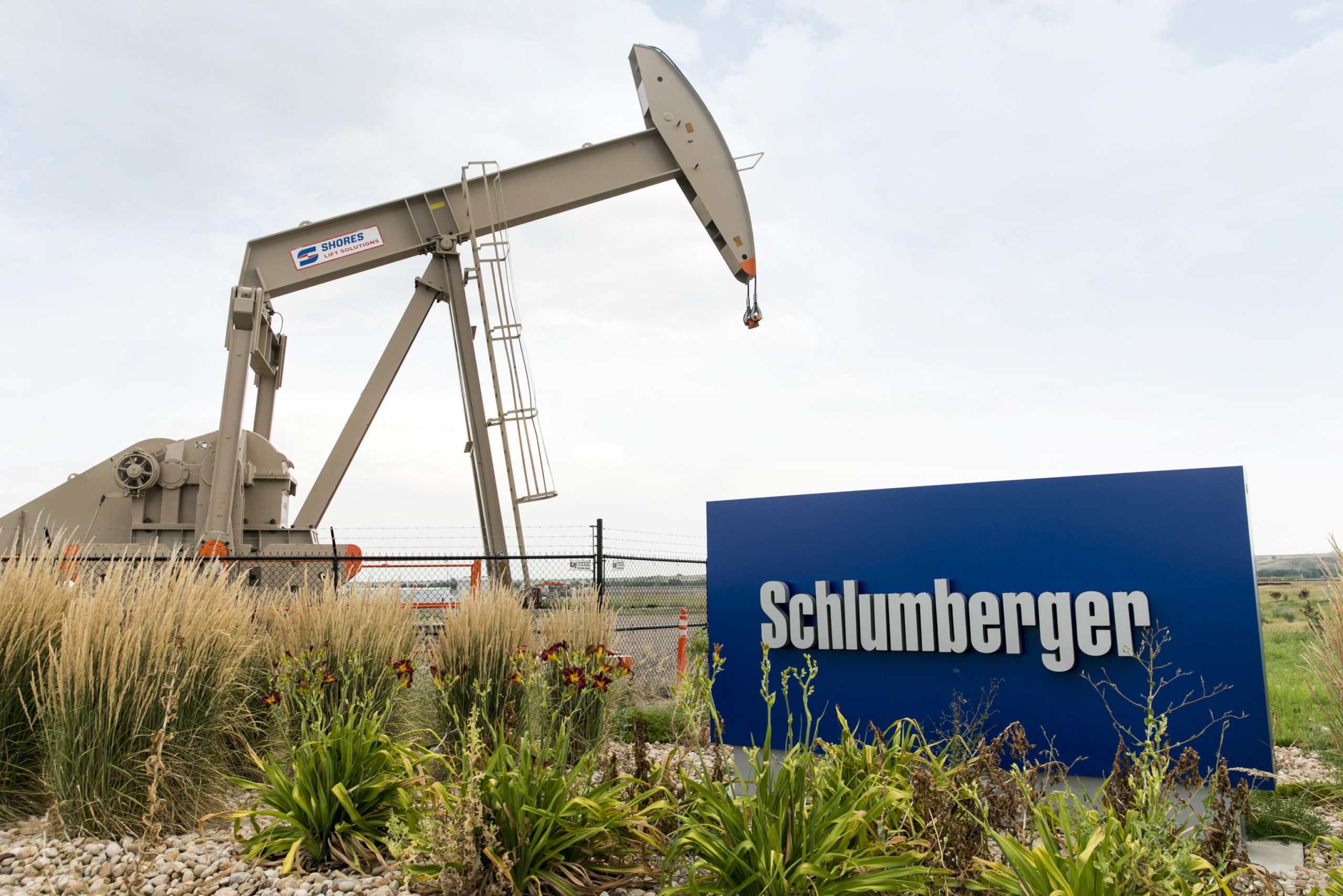 A logo sign and oil pump outside of a facility occupied by Schlumberger in Windsor, Colorado, on July 21, 2018. (Photo by Kristoffer Tripplaar/Sipa USA)(Sipa via AP Images)