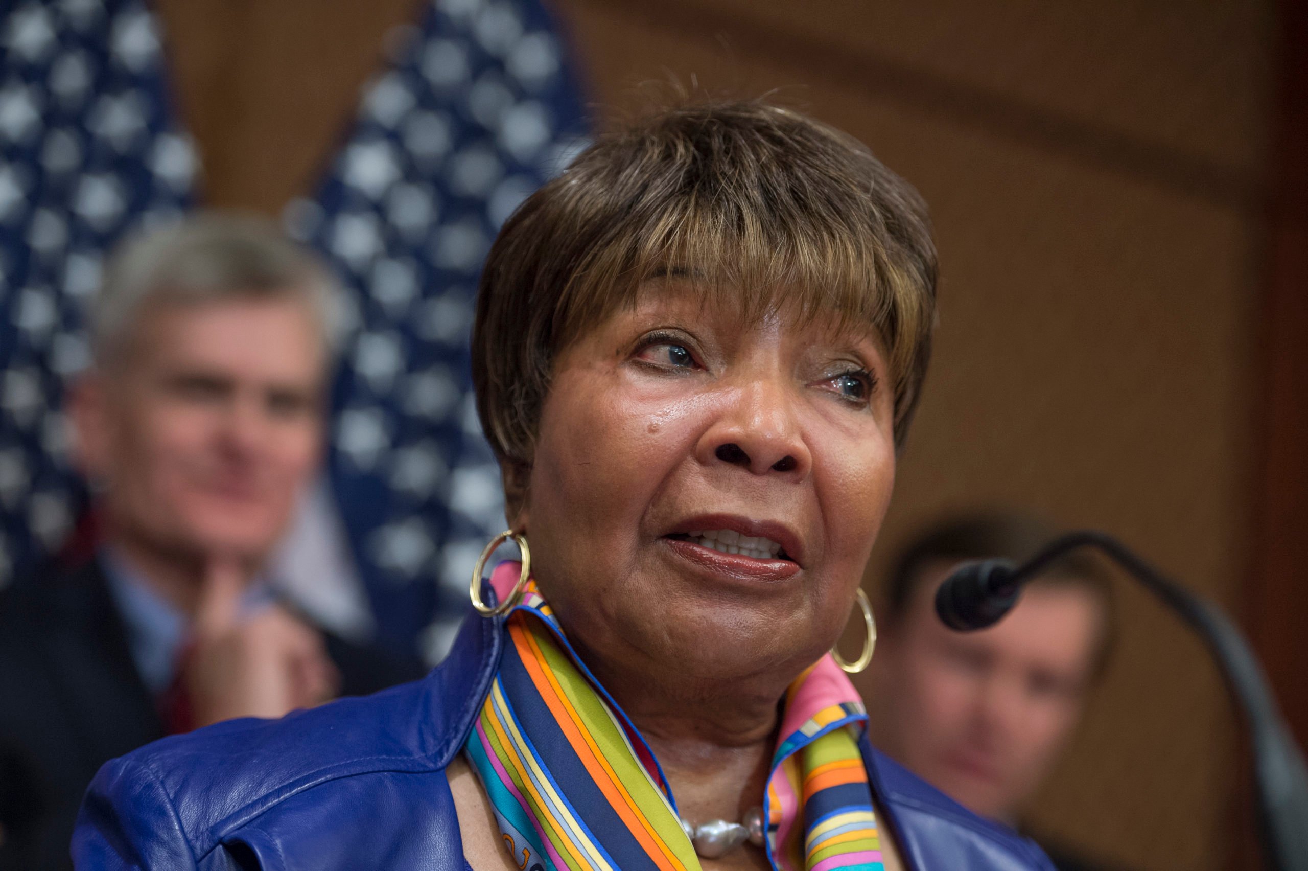 A color photo of Eddie Bernice Johnson, wearing a blue jacket, gold hoop earrings and a rainbow scarf.