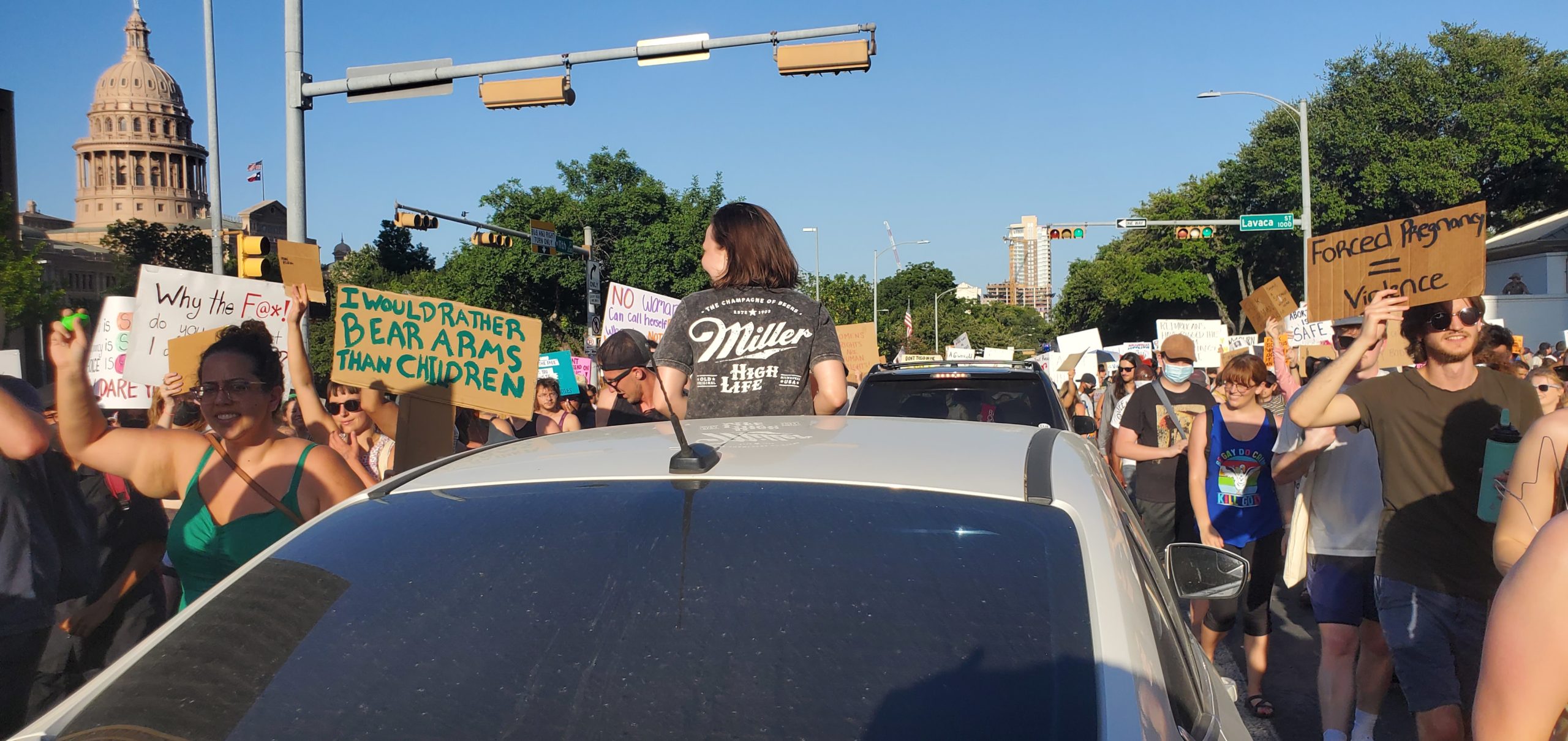A driver peaks through the sunroof of her stopped car to cheer on protesters