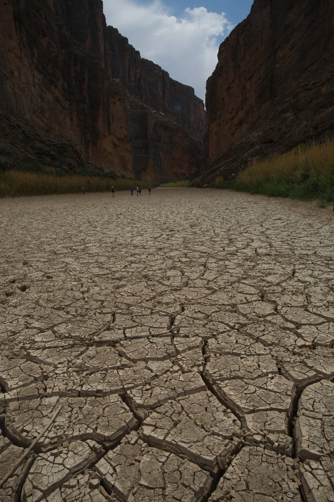 The Rio Grande runs dry at Santa Elena Canyon. The earth of the Rio Grande river bed is so dry, it's become cracked and broken. Tall canyon walls climb to either side over the shattered earth.