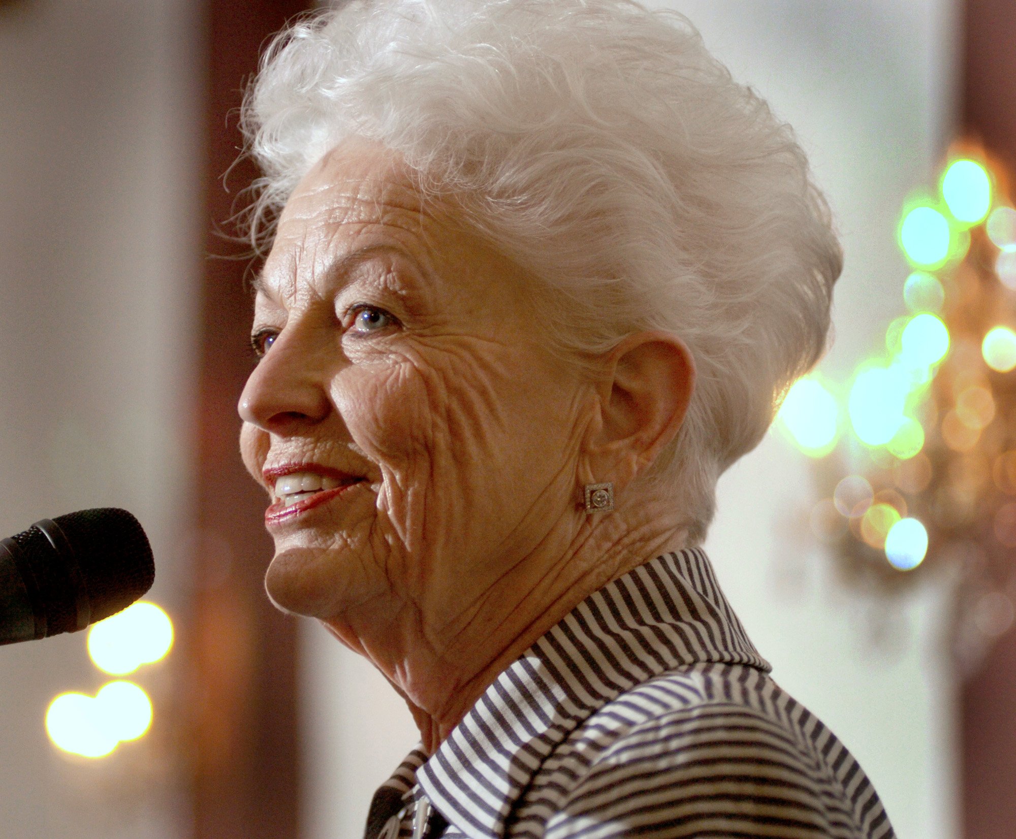 Ann Richards smiles as she speaks at a microphone.